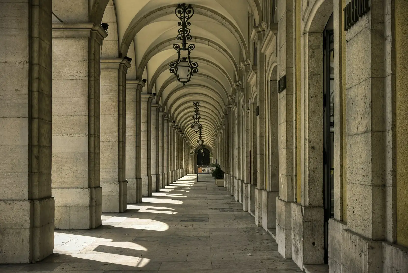 Arcadas da Praça do Comércio, em Lisboa, com luz do sol no chão de pedra