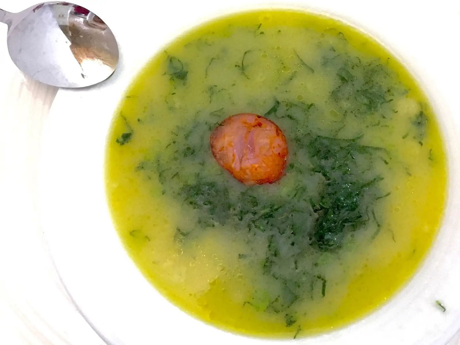 Prato de caldo verde com uma rodela de chouriço, visto de cima