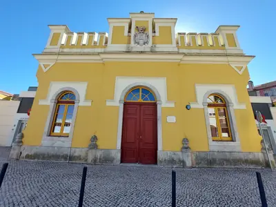 Fachada amarela do antigo Matadouro Municipal de Santarém, hoje Loja do Cidadão, com porta vermelha e janelas em arco