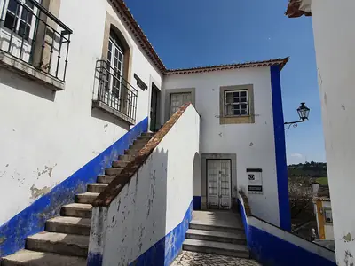 Edifício da Segurança Social em Óbidos, uma casa branca com barras azuis e escada exterior